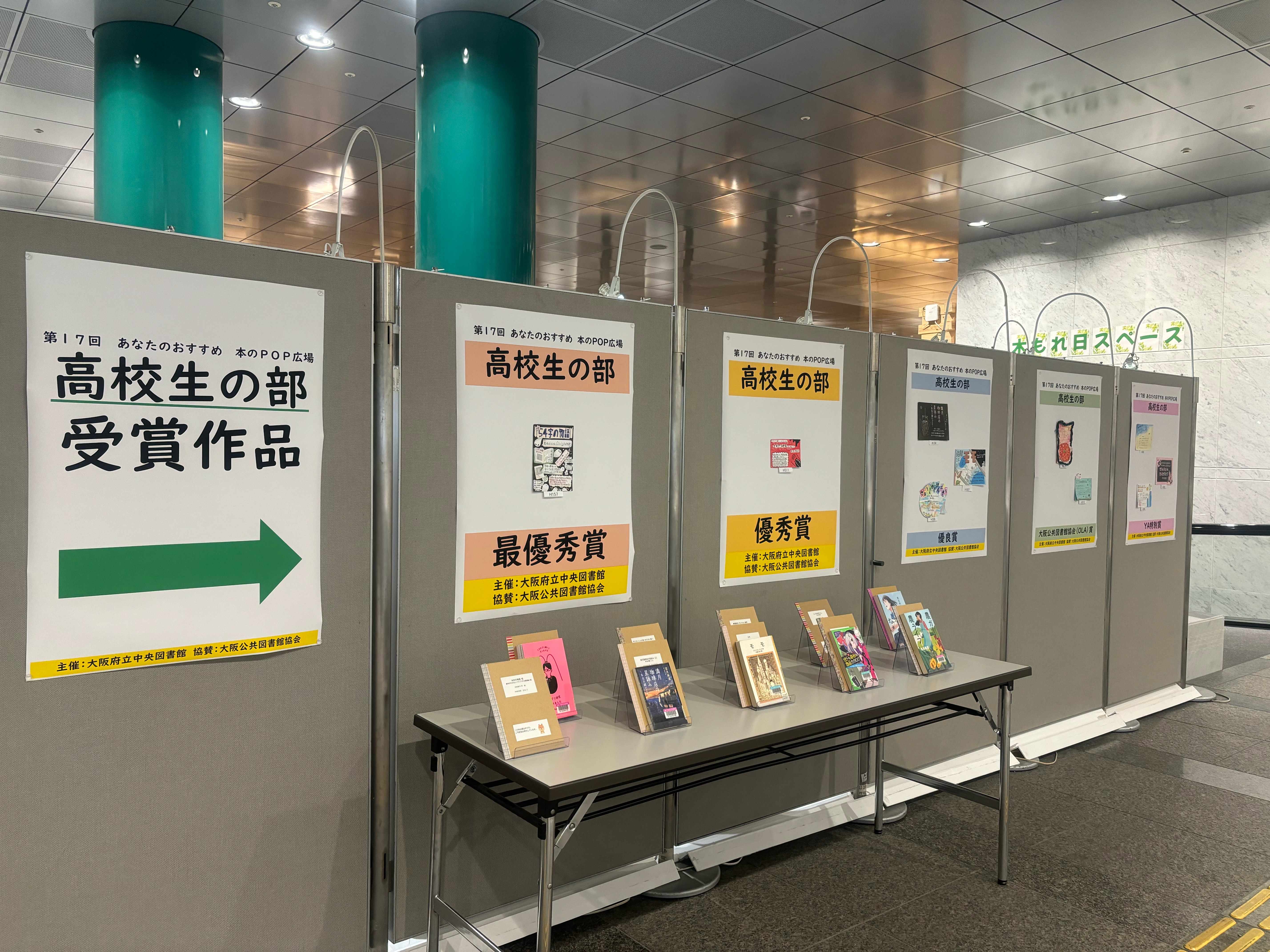 高校生の部:並んだボードの左から右奥にかけて、高校生の部受賞作品のポスターから始まり、ボードに受賞作のPOP、その前の机に本が展示されている風景写真