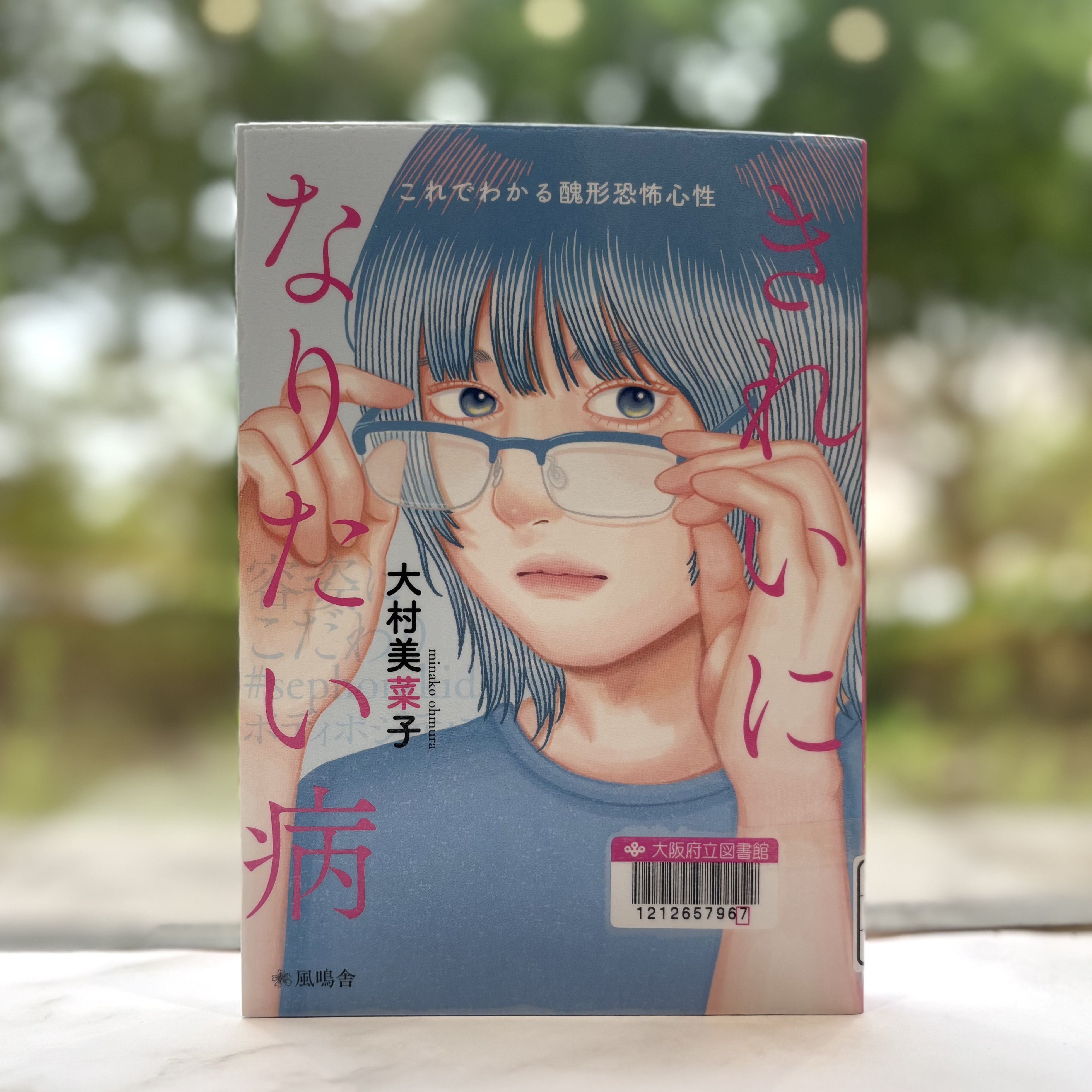 『きれいになりたい病：これでわかる醜形恐怖心性』の表紙画像。メガネの弦を両手で持ち、正面を見る女性のイラスト。