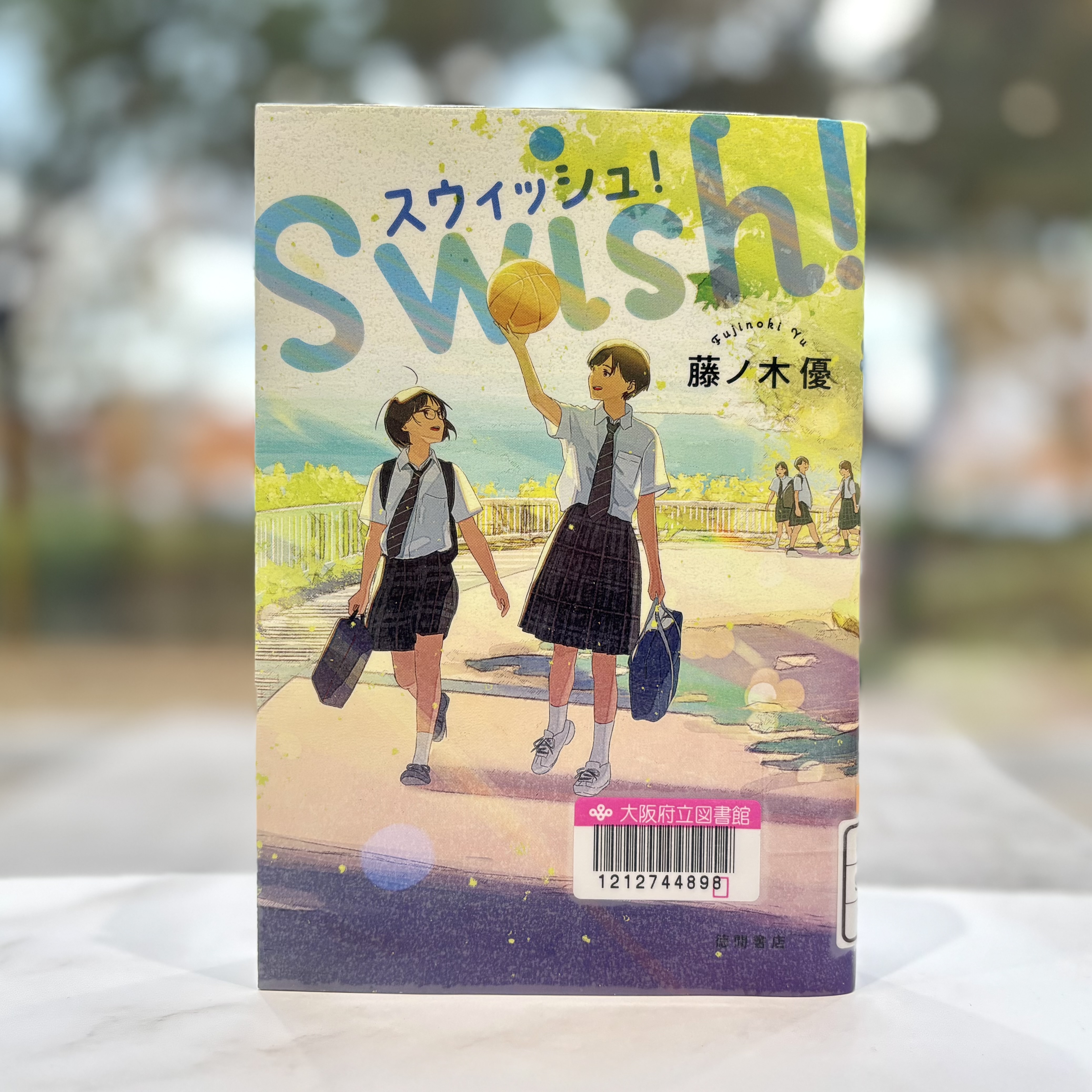 『スウィッシュ!　Swish!』の表紙画像。制服を着たバスケットバールを持つ女の子とメガネをかけた女の子が道を歩いているイラスト。