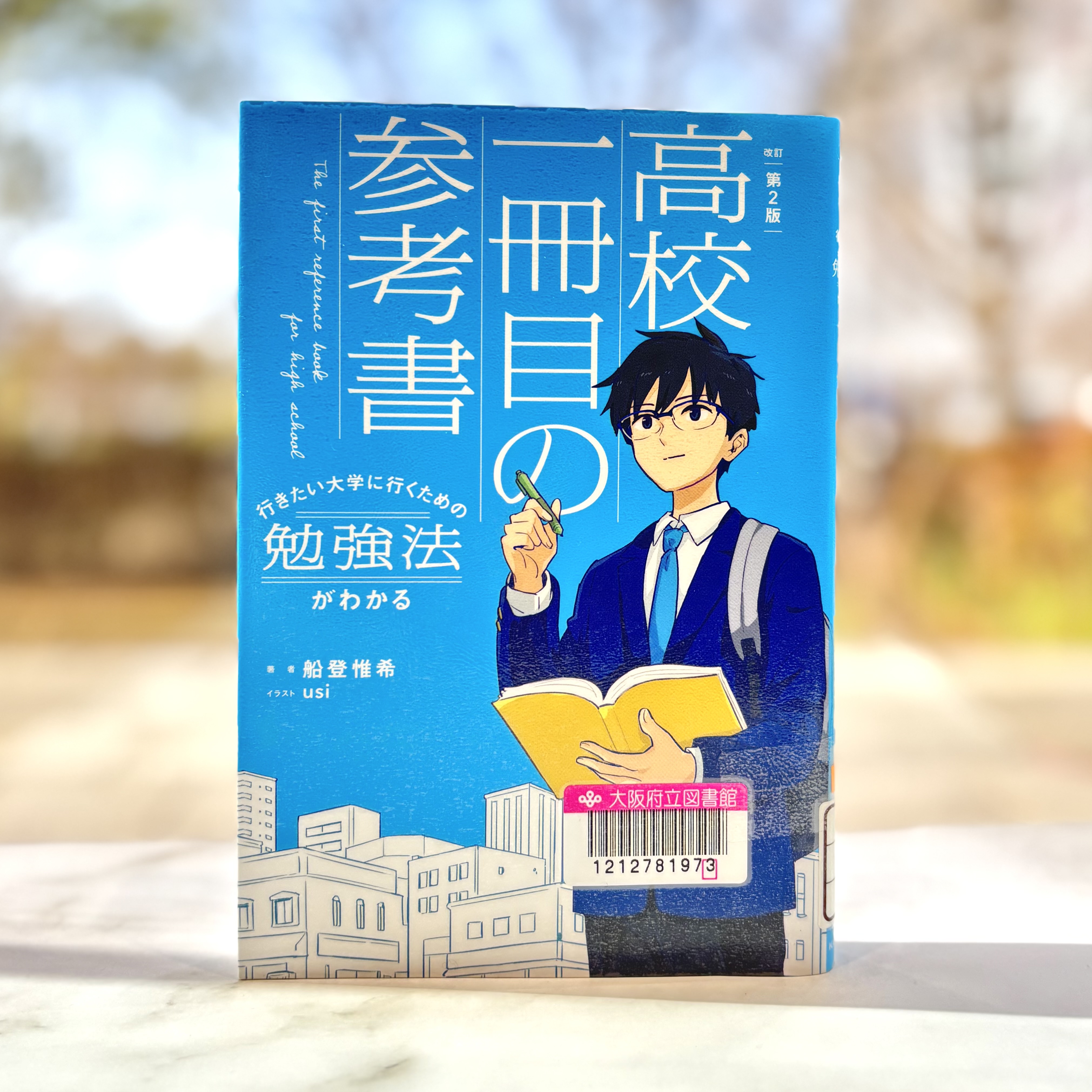 『高校一冊目の参考書：行きたい大学に行くための勉強法がわかる　改訂第2版』の表紙画像。青の背景にノートとペンを持った、学生服の男の子のイラストが描かれている。