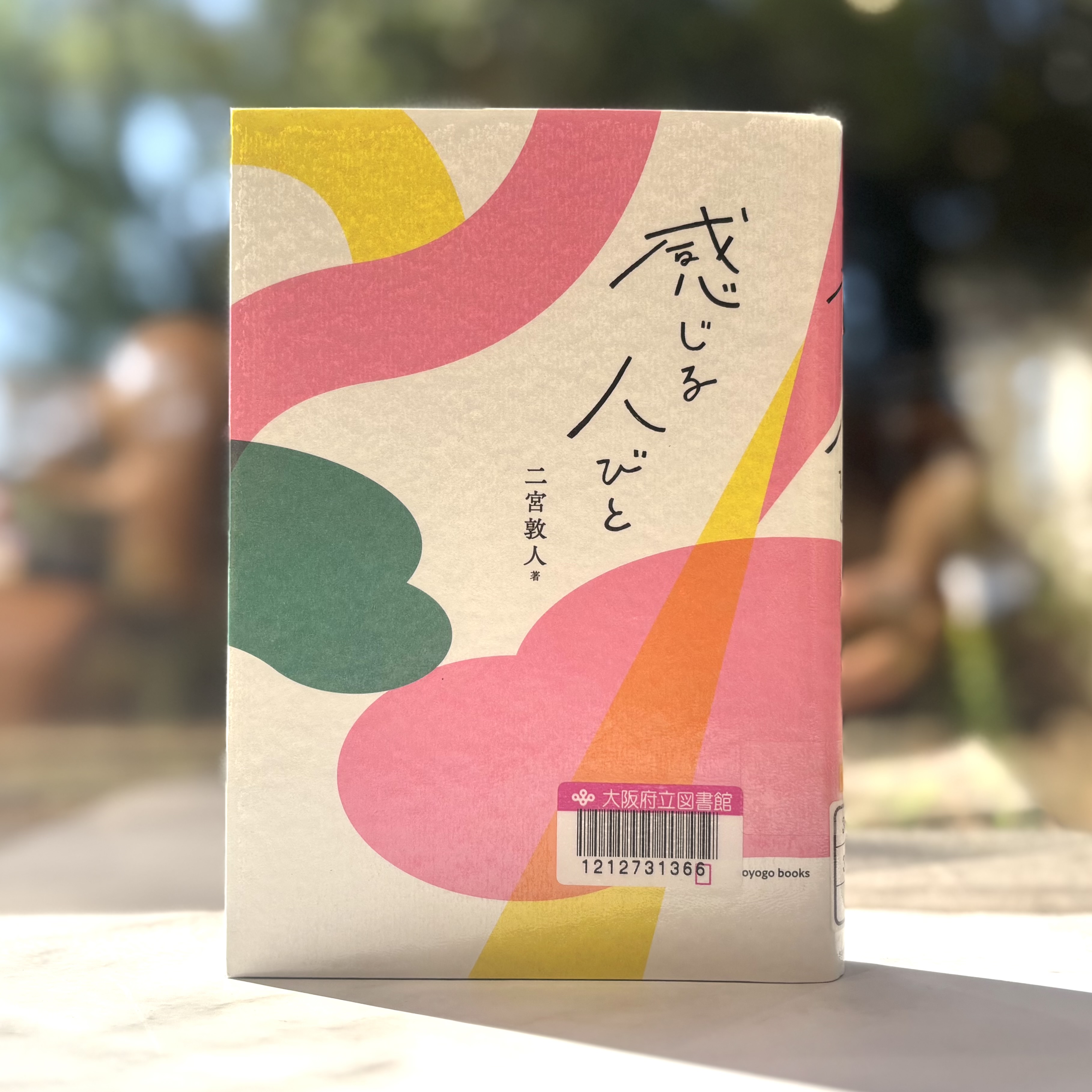 『感じる人びと』の表紙画像。白い背景に黄色やピンクの装飾がされている。