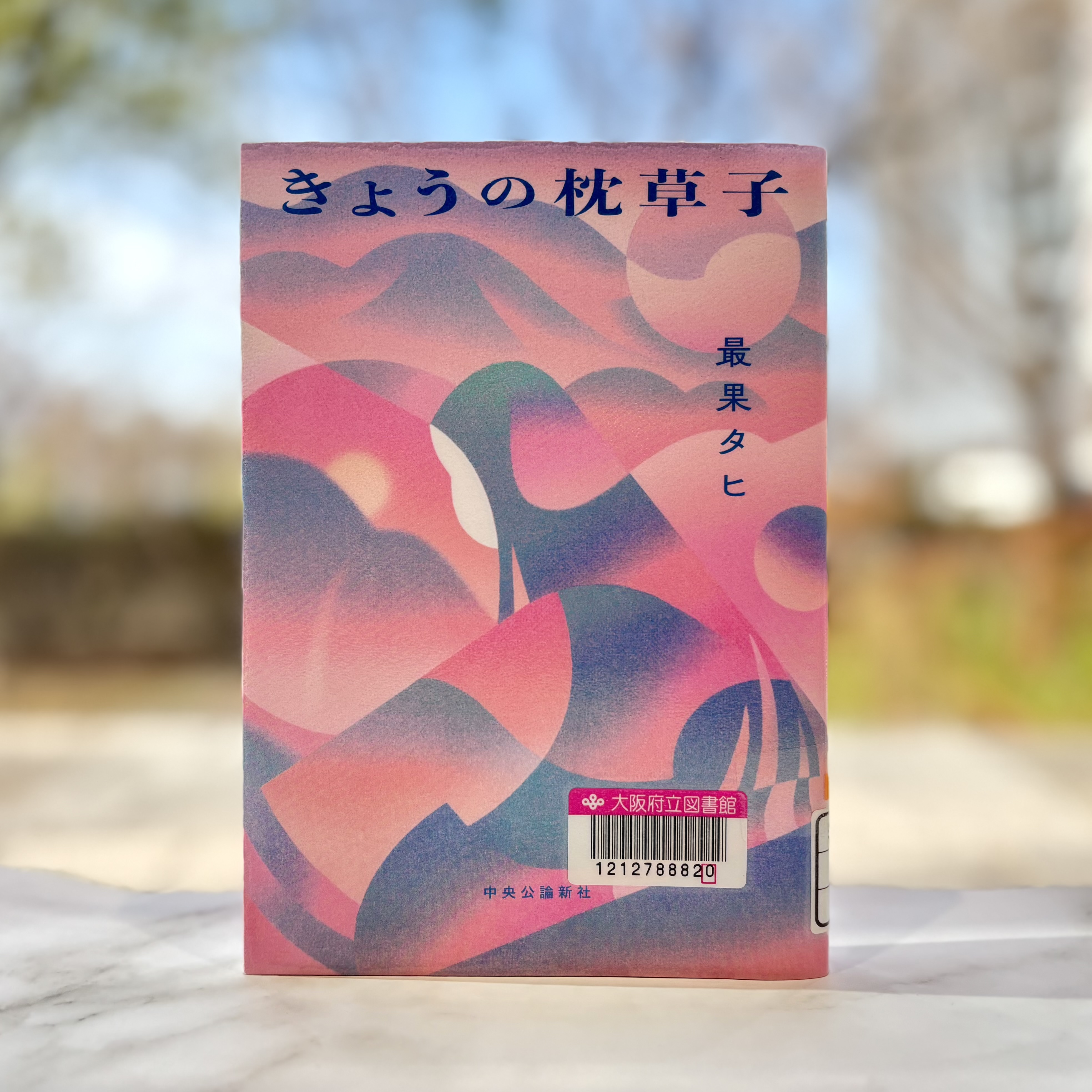 『きょうの枕草子』の表紙画像。ピンク、紫、青のグラデーションで、山並みや月を思わせる抽象的で鮮やかなイラストの中に横向きの平安風の女性が描かれている。