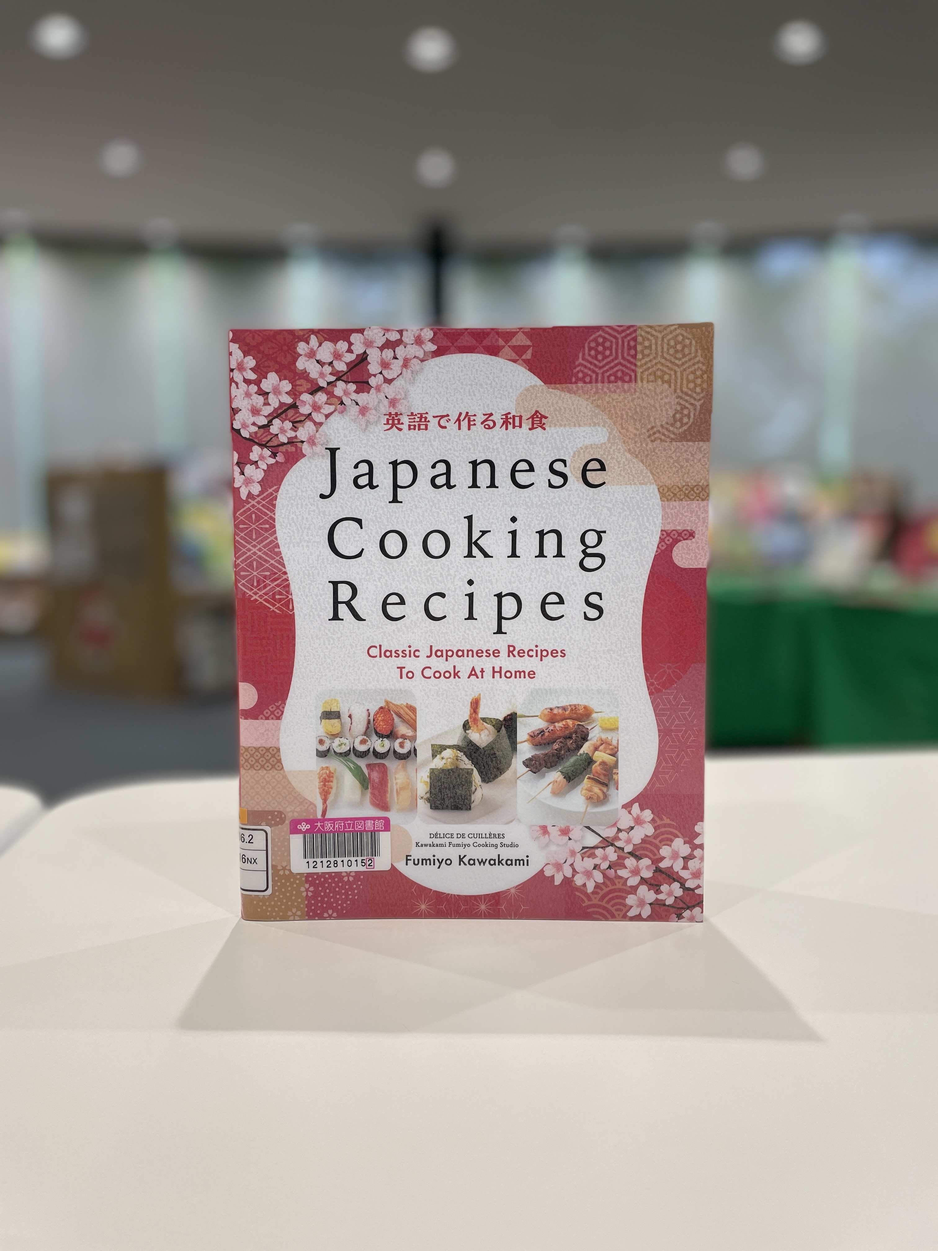 『Japanese Cooking Recipes：英語で作る和食　Classic Japanese Recipes To Cook At Home』の表紙画像。赤い表紙に寿司やおにぎり、やきとりの写真が掲載されている。