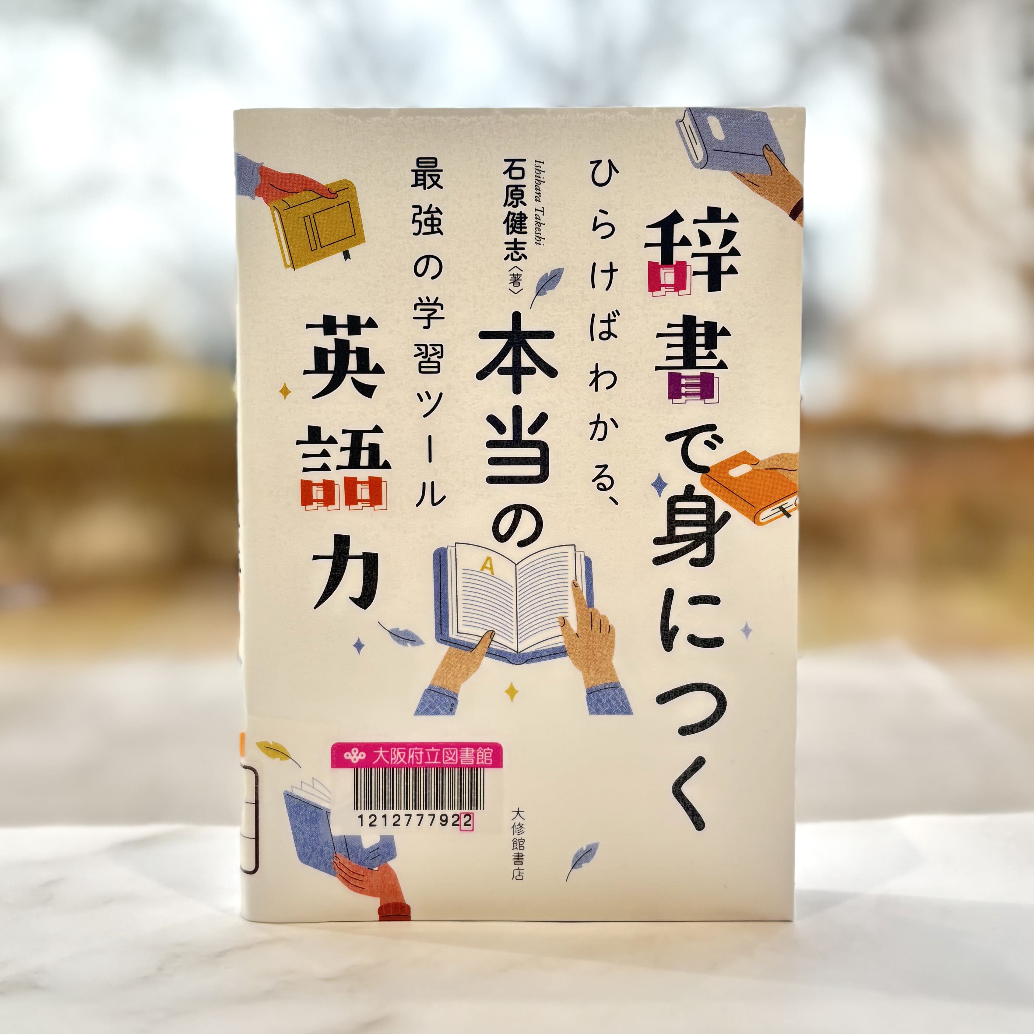 『辞書で身につく本当の英語力：ひらけばわかる、最強の学習ツール』の表紙画像。タイトルが縦書きで表紙いっぱいに大きく書かれ、間に様々な辞書とそれを持つ手がが描かれている。