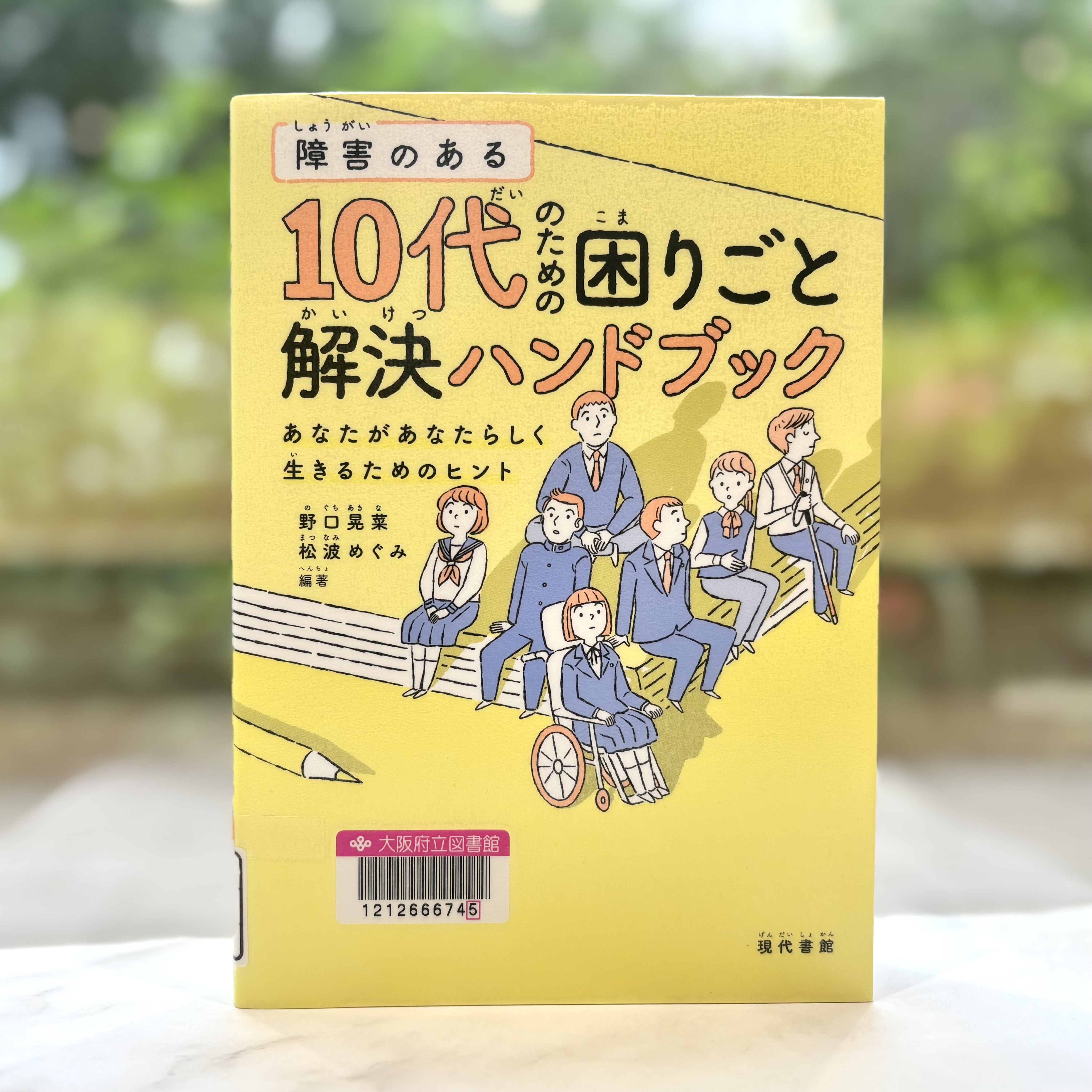 『障害のある10代のための困りごと解決ハンドブック：あなたがあなたらしく生きるためのヒント』の表紙画像。黄色い背景に本の上にのる学生たちのイラスト。