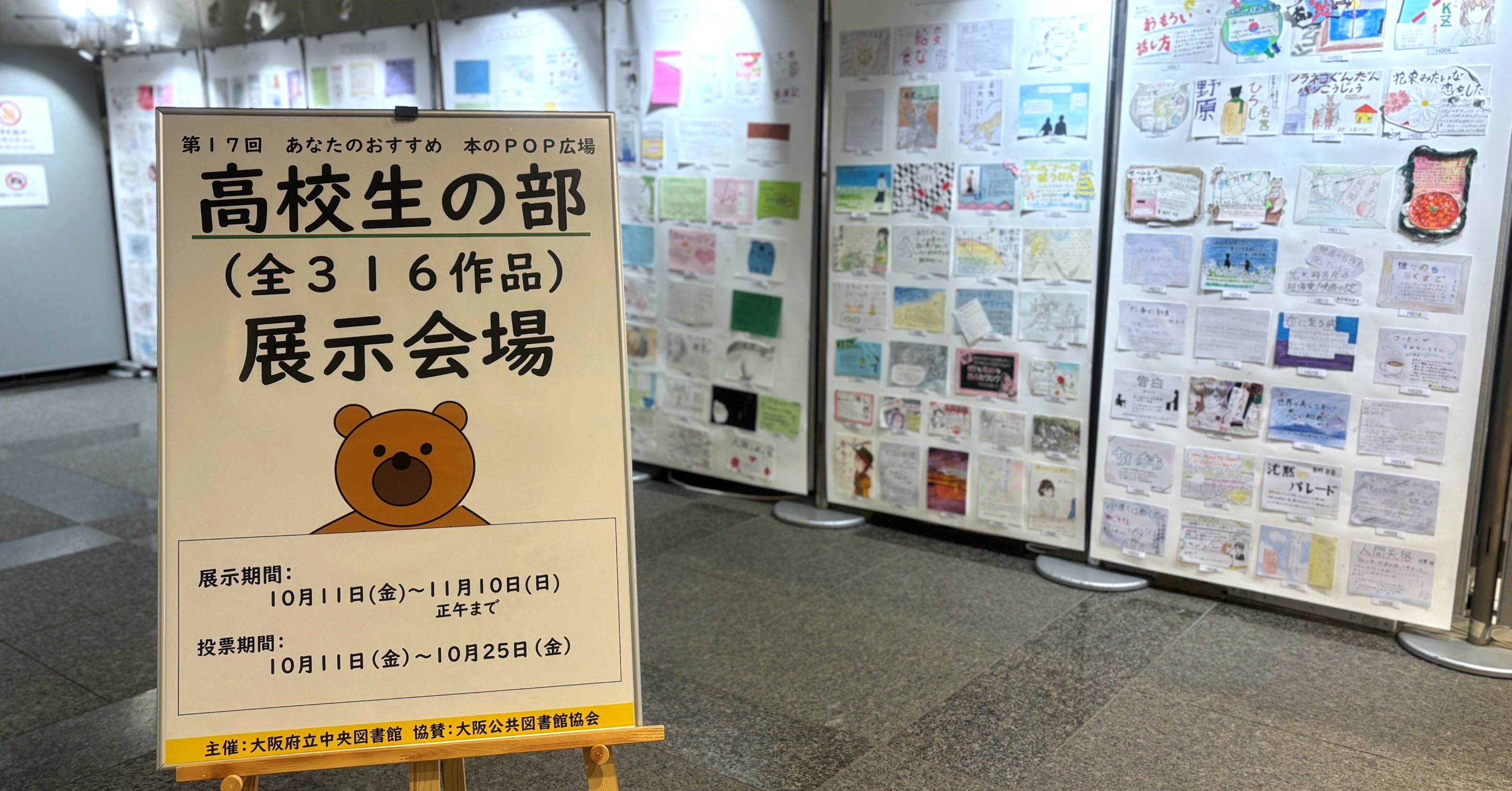 高校生の部:展示コーナーAで開催している様子。手前に看板、右手から奥にかけて展示されている風景写真