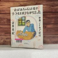 木の板を背景に『おばあちゃんは猫でテーブルを拭きながら言った　世界ことわざ紀行』の表紙