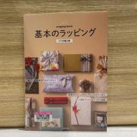 木の壁を背景に『基本のラッピング　丁寧な写真付き解説でわかりやすい』の表紙