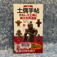 青地に白い模様の紙を背景に『土偶手帖　おもしろ土偶と縄文世界遺産』の表紙